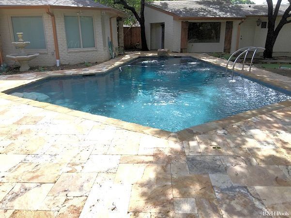 There is a large swimming pool in the backyard of a house.