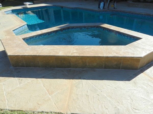 A swimming pool with a hot tub in the middle of it