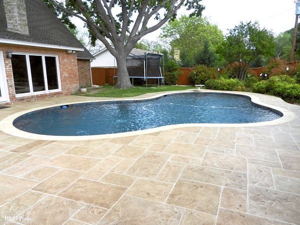 A large swimming pool is in the backyard of a house
