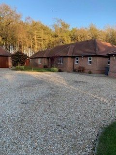 before A large brick house with a gravel driveway in front of it.