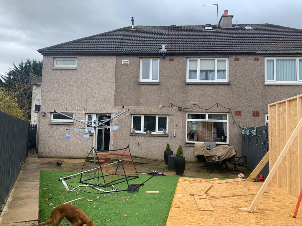 A dog is standing in front of a house that is being built.