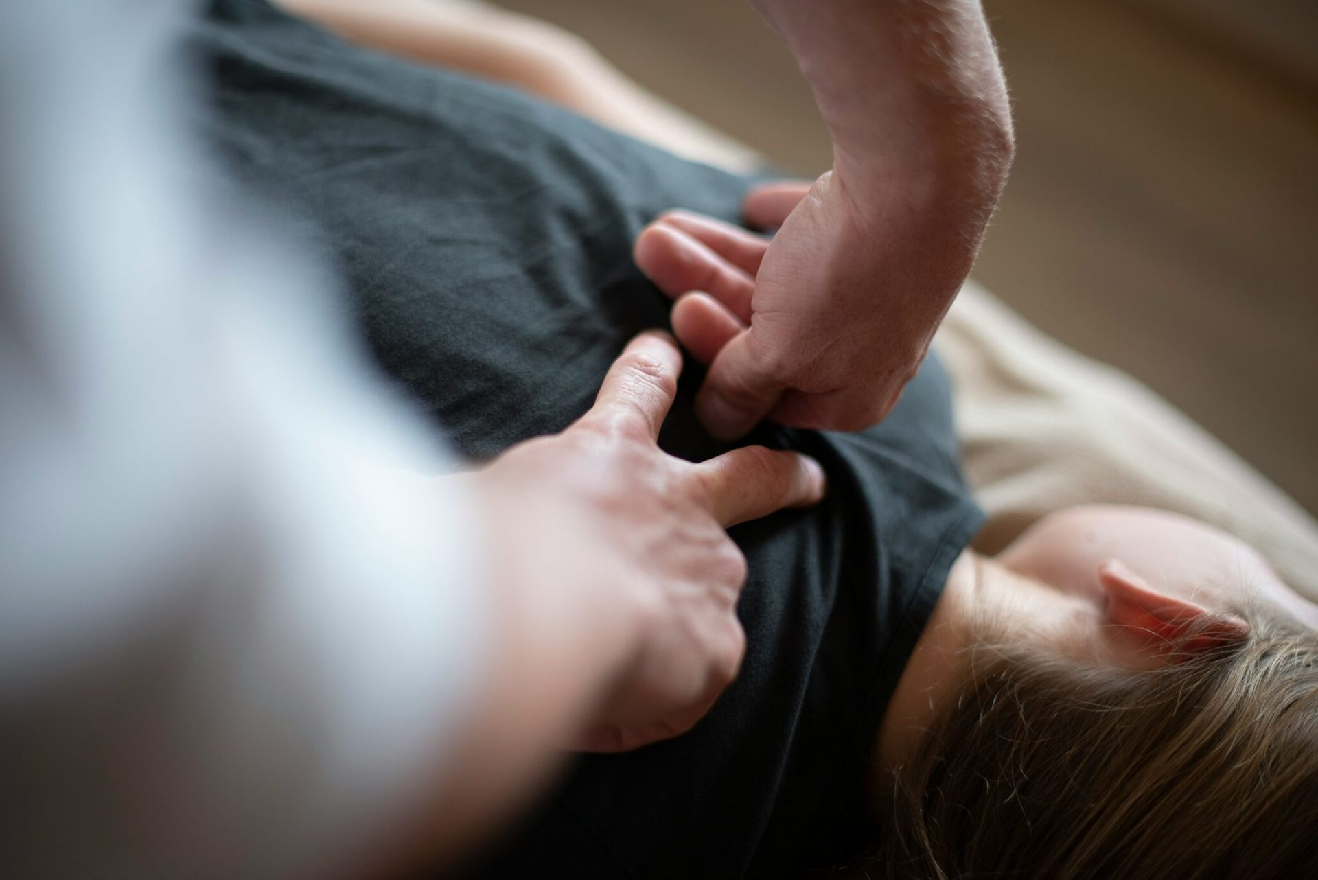A practitioner performs manual back therapy on a person lying down.