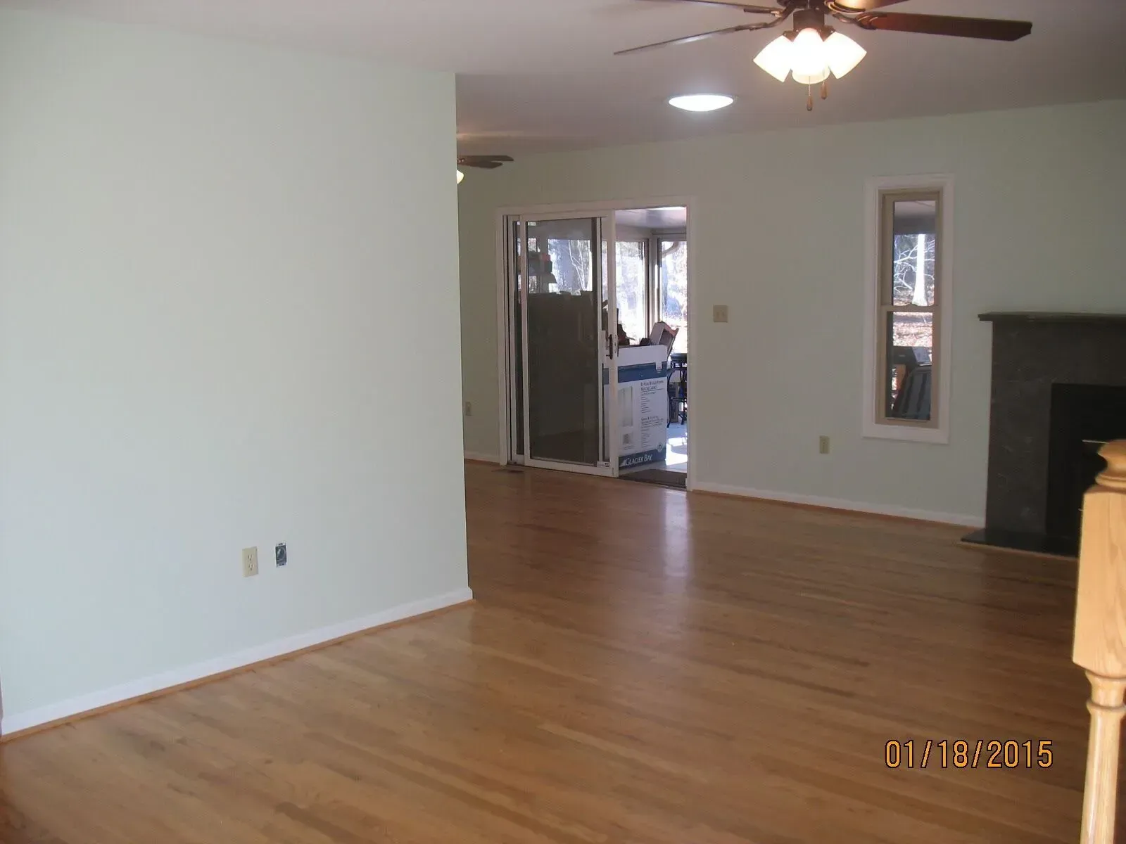 An empty living room with hardwood floors and a ceiling fan