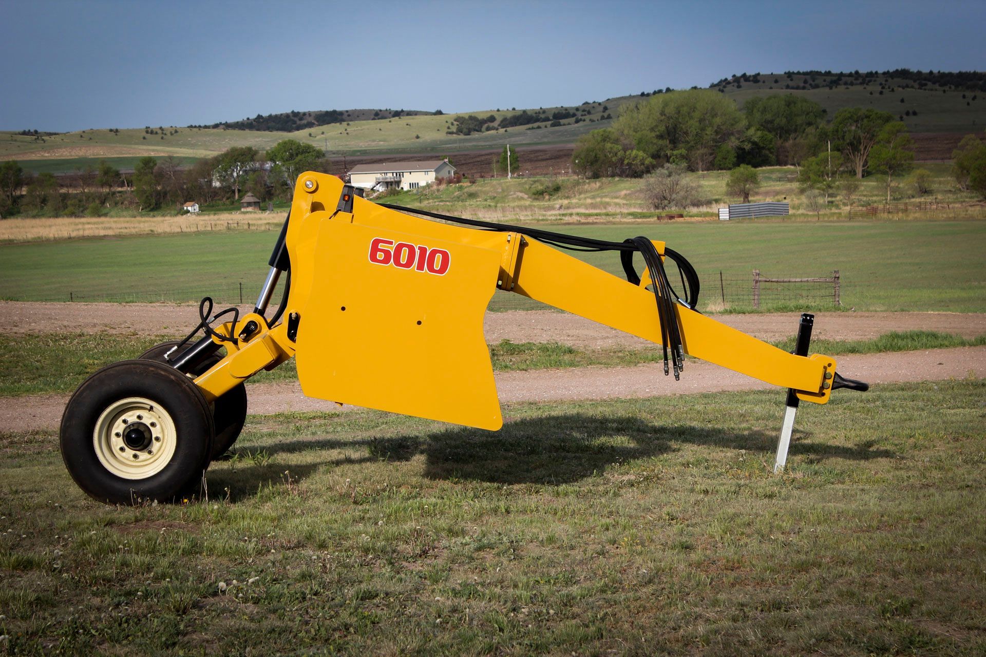 A yellow scraper is parked in a grassy field.