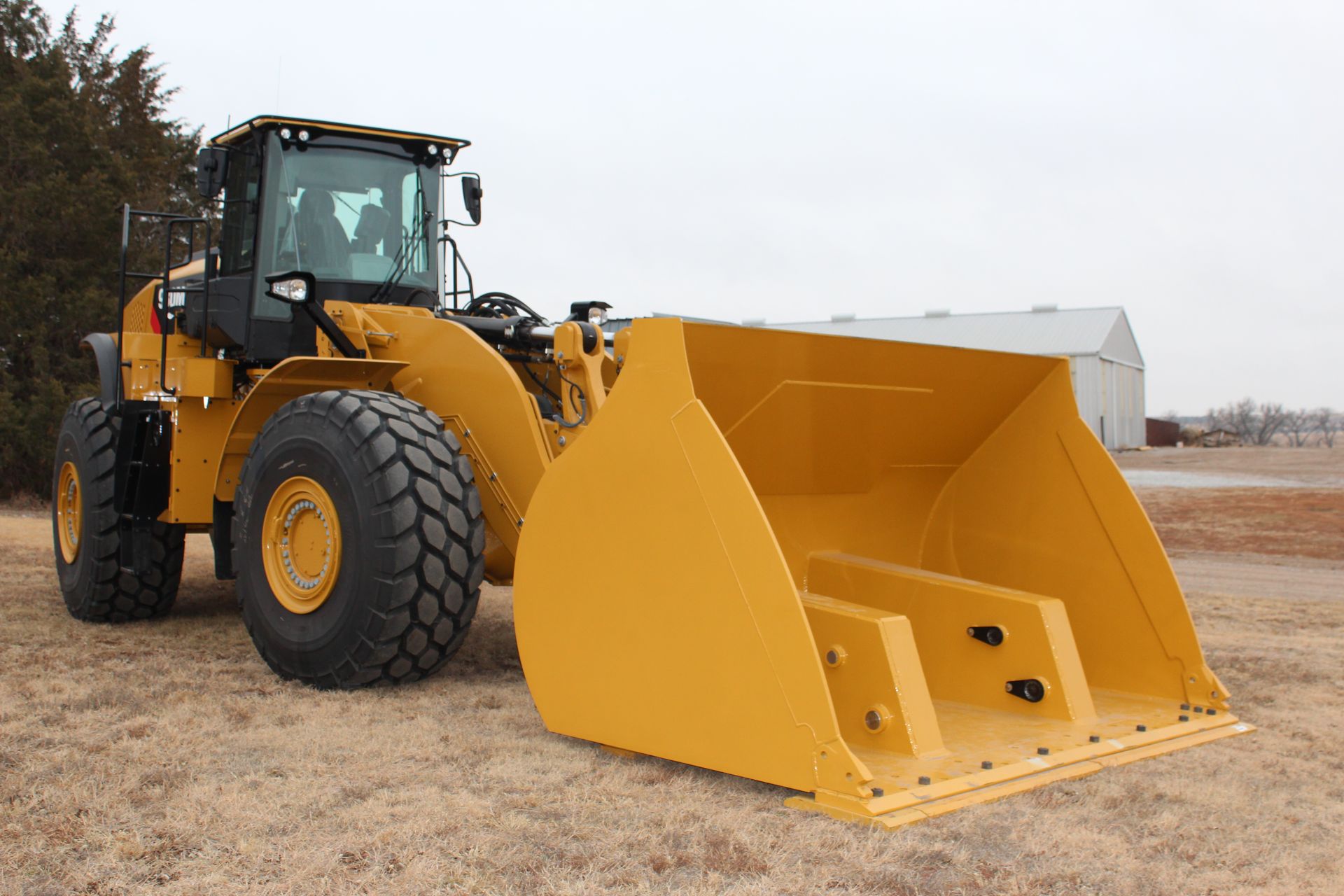 A yellow bulldozer with a large rollout bucket is parked in a field.