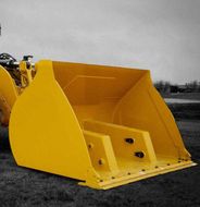 A large yellow bucket sits on the ground next to a tractor