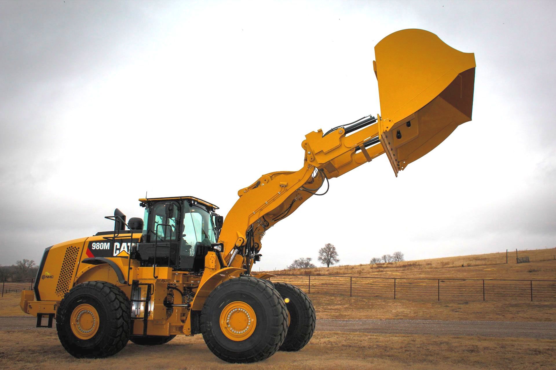 A yellow bulldozer with a large rollout bucket is parked in a field