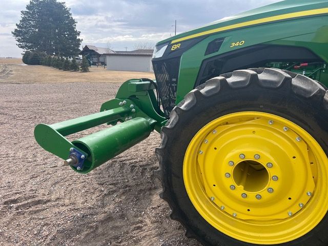 A green and yellow john deere tractor with a stalk roller