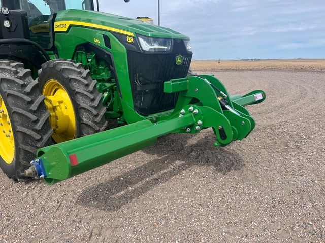 A green and yellow john deere tractor with a stalk roller