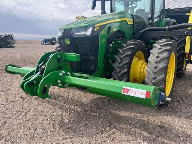 A green and yellow john deere tractor with a stalk roller