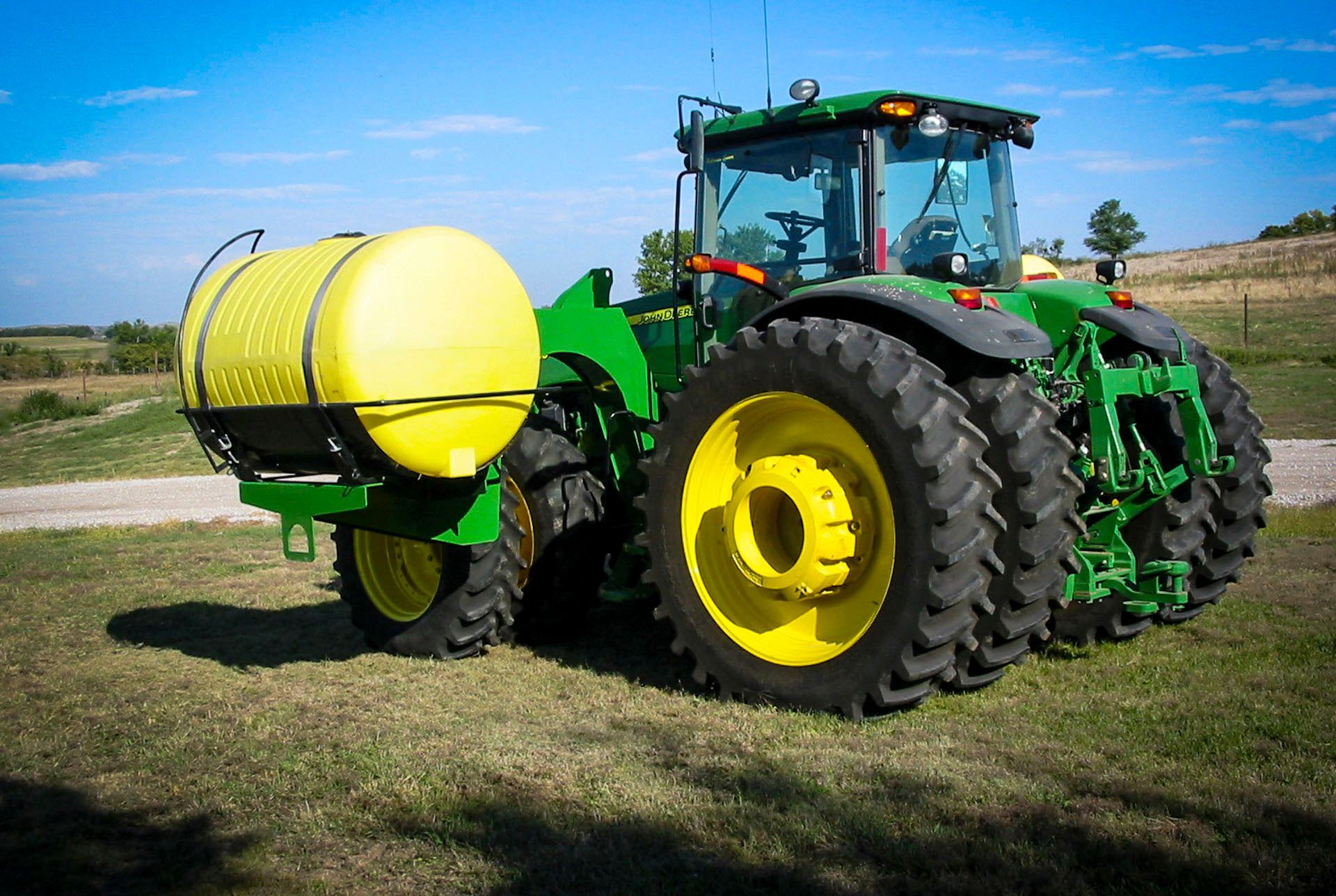 A green and yellow tractor with a yellow tank attached to it