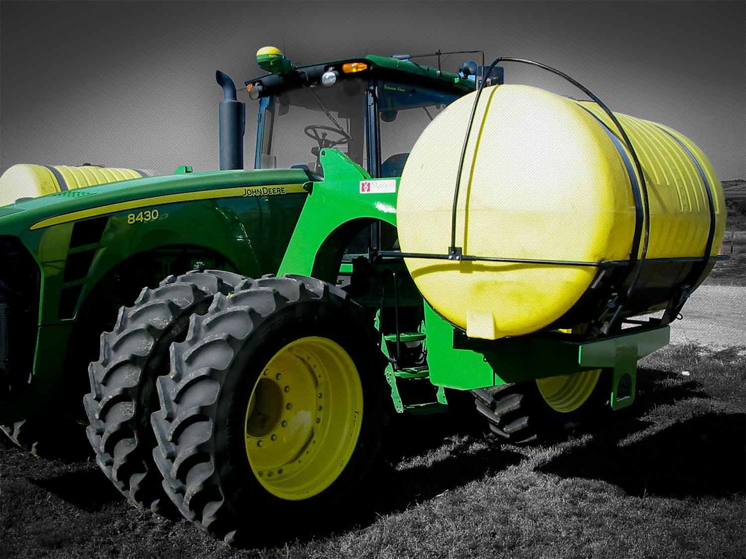 A green john deere tractor with a yellow tank attached to it