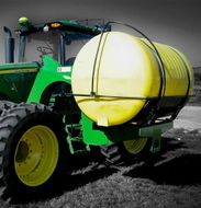 A green john deere tractor with a yellow tank attached to it