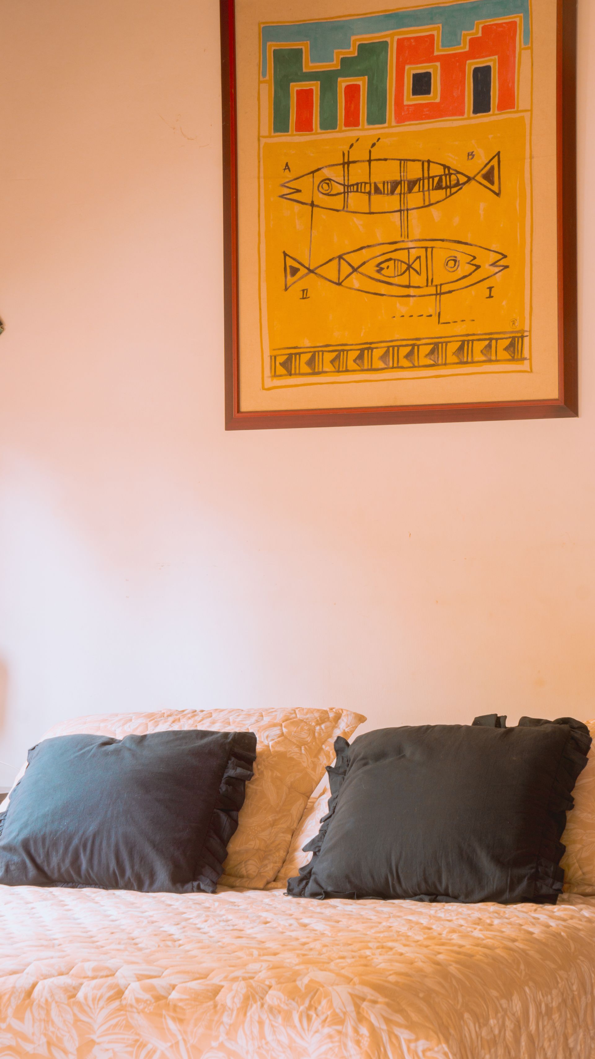 Cama con dos almohadas gris oscuro y una obra de arte en la pared.