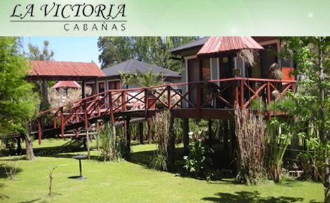 La Victoria Cabanas: Cabañas con techos rojos y puente de madera sobre un patio con césped.
