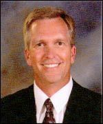 A man in a suit and tie is smiling for the camera.