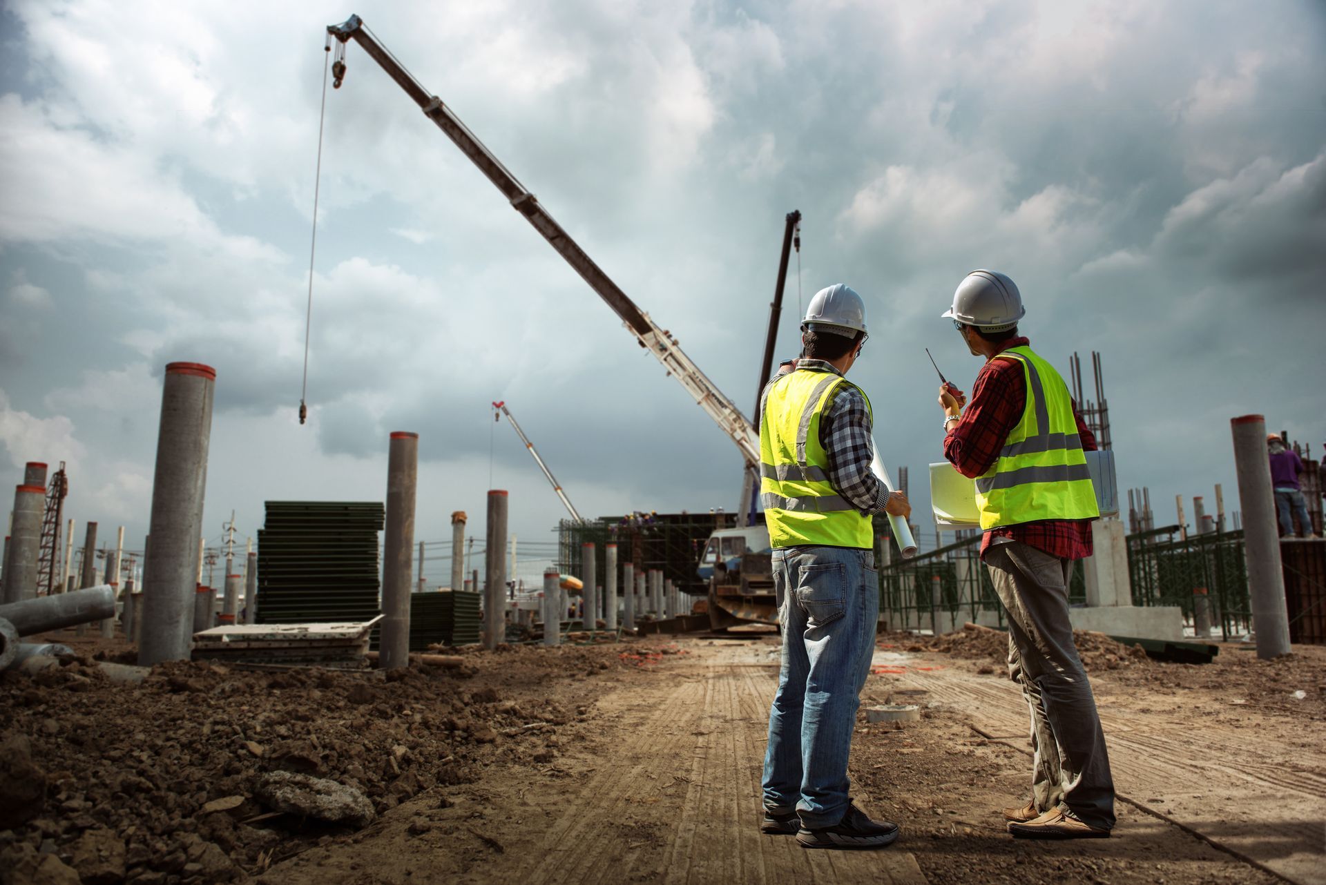 Two construction engineers are seeing a demolition crane from afar, in a demolition site. Two construction engineers are seeing a demolition crane from afar, in a demolition site.