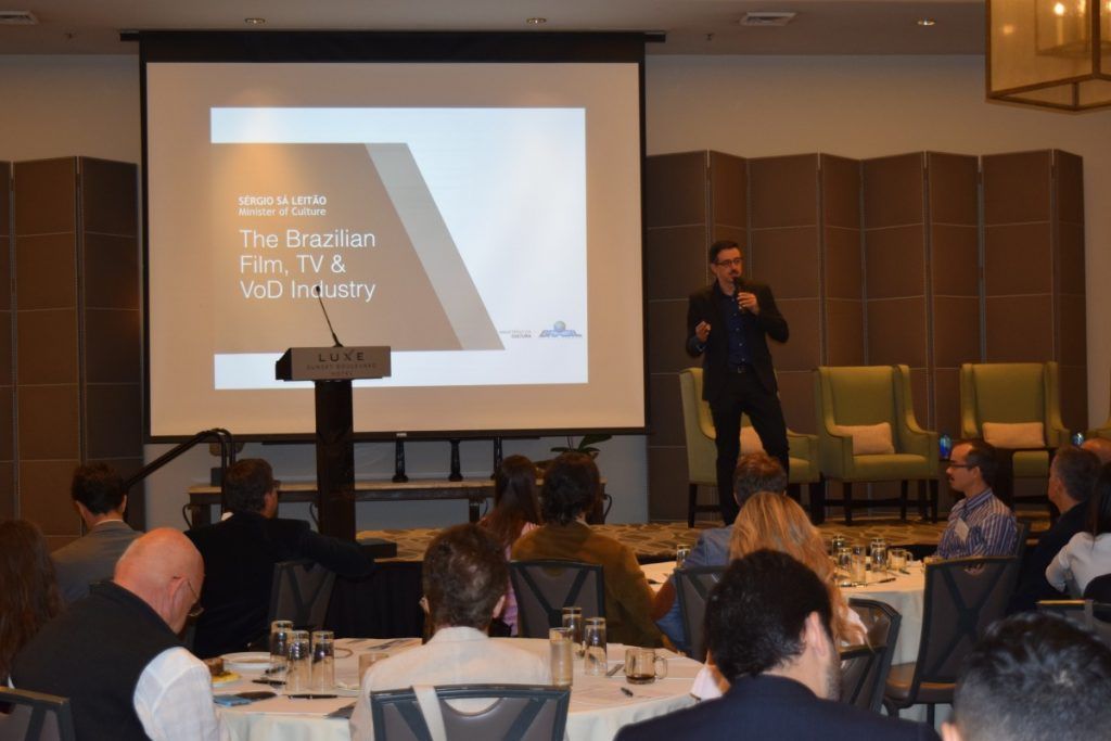 A man presenting to a seated audience at a conference, focusing on film, TV & web industry.