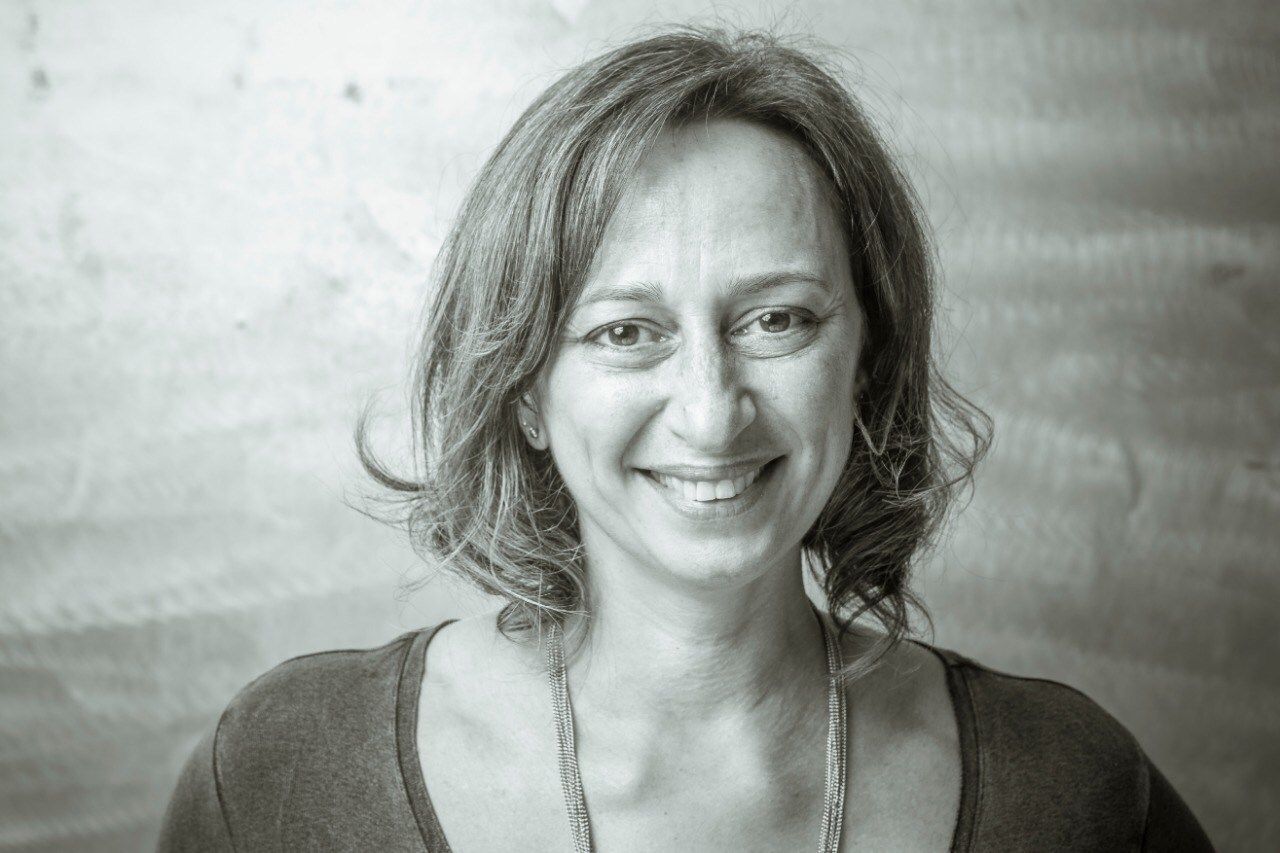 Smiling woman with short hair, wearing a necklace, in sepia tones.