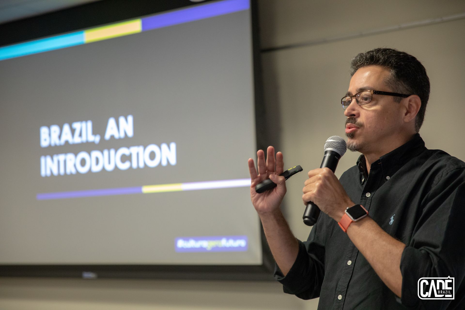 Man speaking at a presentation on Brazil, gesturing with his hand. Text on the screen: