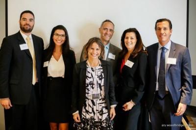 Group of six people in business attire posing for a photo against a white background.