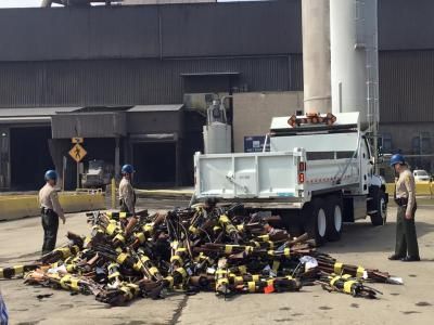 Law enforcement officers inspect a pile of confiscated rifles dumped from a truck in an industrial area.