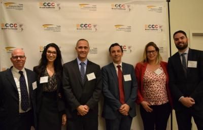 Six people posing formally in front of a banner.