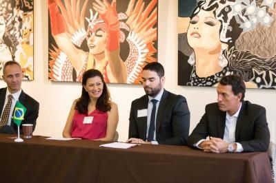 Four people seated at a table, in front of Brazilian art. They appear to be at a conference or meeting.