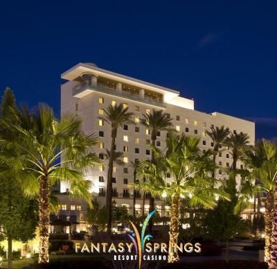 Fantasy Springs Resort Casino at night, white building, palm trees, and a lit sign.
