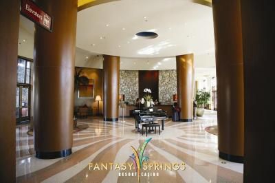 Hotel lobby with brown columns, patterned floors, and a piano, logo in foreground.