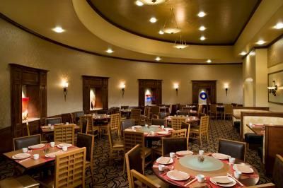 Circular Chinese restaurant with tables set for dining. Dim lighting.