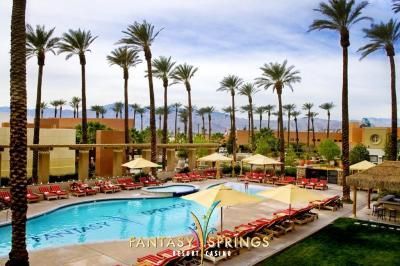 Pool area at Fantasy Springs Resort Casino, Palm Springs, with palm trees and lounge chairs.