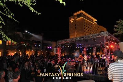 Nighttime outdoor concert at Fantasy Springs Resort Casino. Band on stage, crowd watching, tall building in background.