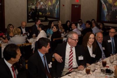 People in business attire at a restaurant, seated at tables, engaged in conversation.