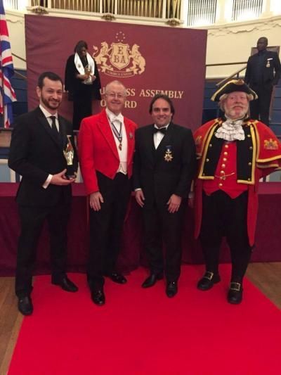 Four men on a red carpet: one holding a trophy, others in formal wear, Oxford Town Hall.