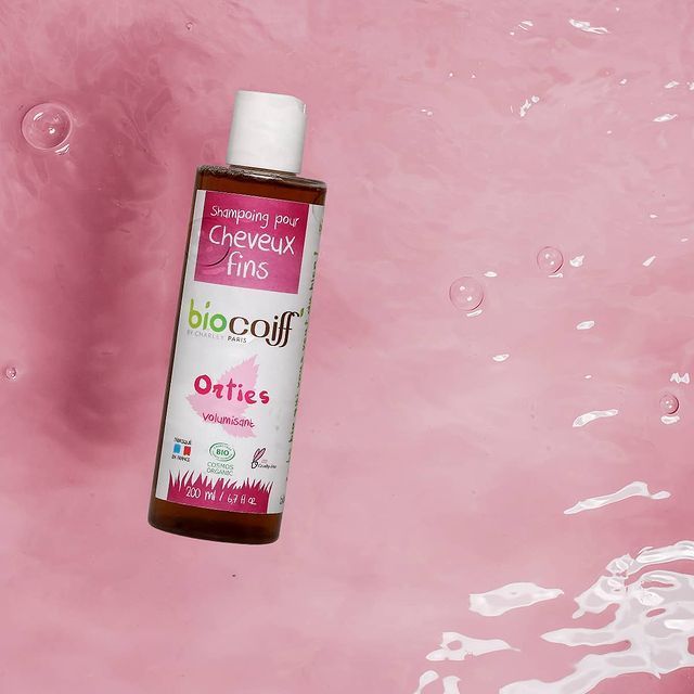 Fles BioOil huidverzorgingsolie op een roze, waterige achtergrond.