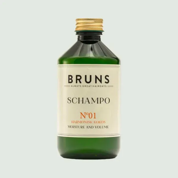 Groene fles BRUNS shampoo met gouden dop en crèmekleurig etiket op een lichte achtergrond