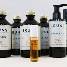 Flesjes Bruns haarverzorgingsproducten en een gouden proefbuisje op een witte achtergrond.