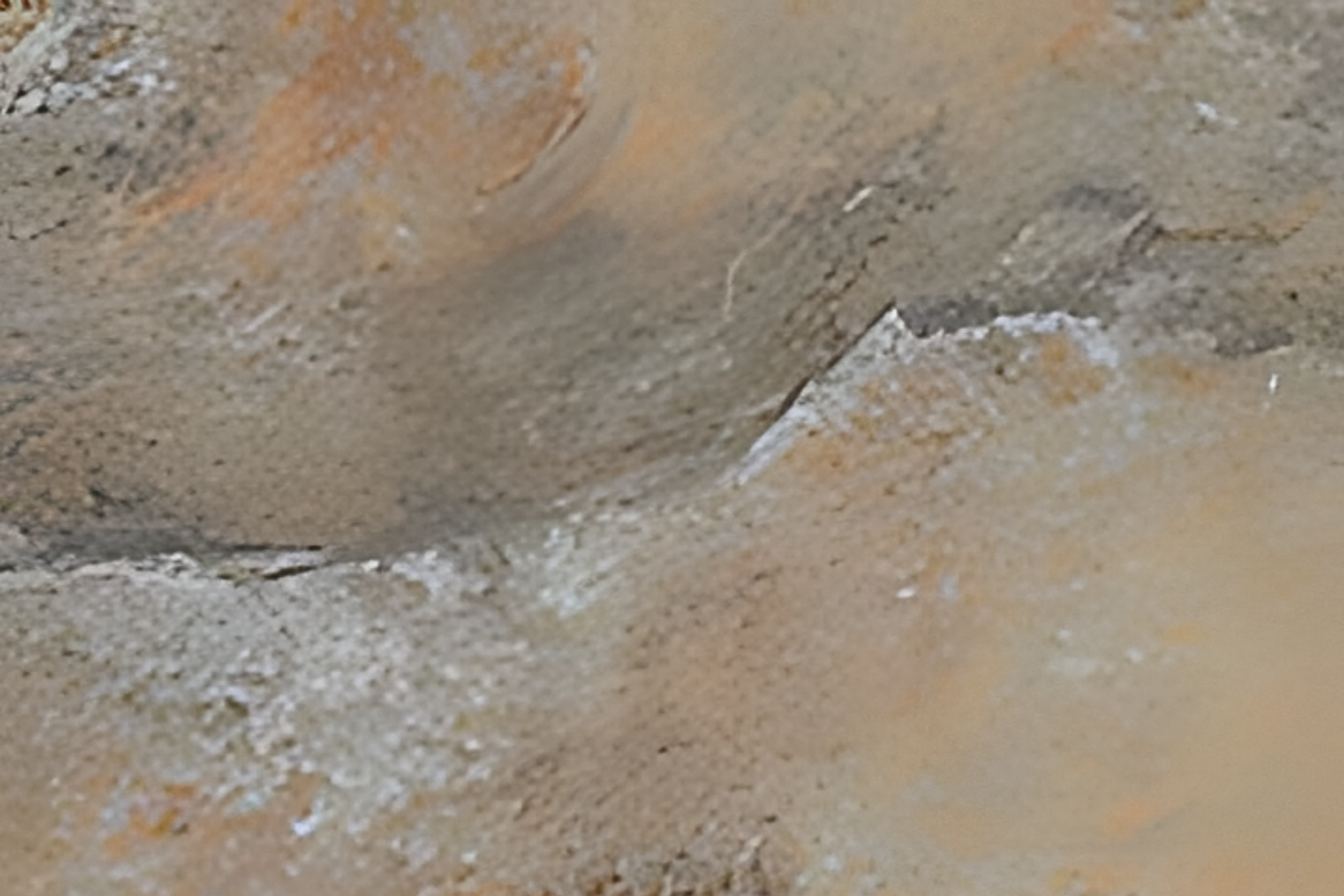 Close-up of beige and gray stone or rock surface with rough texture and white patches