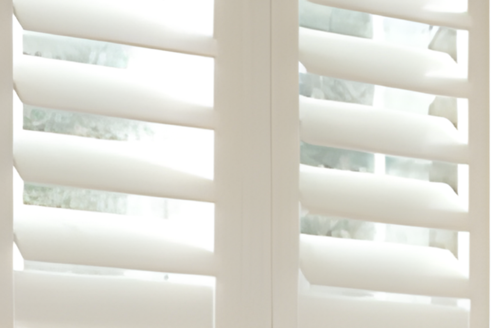 White plantation shutters on a bright window with soft daylight filtering through