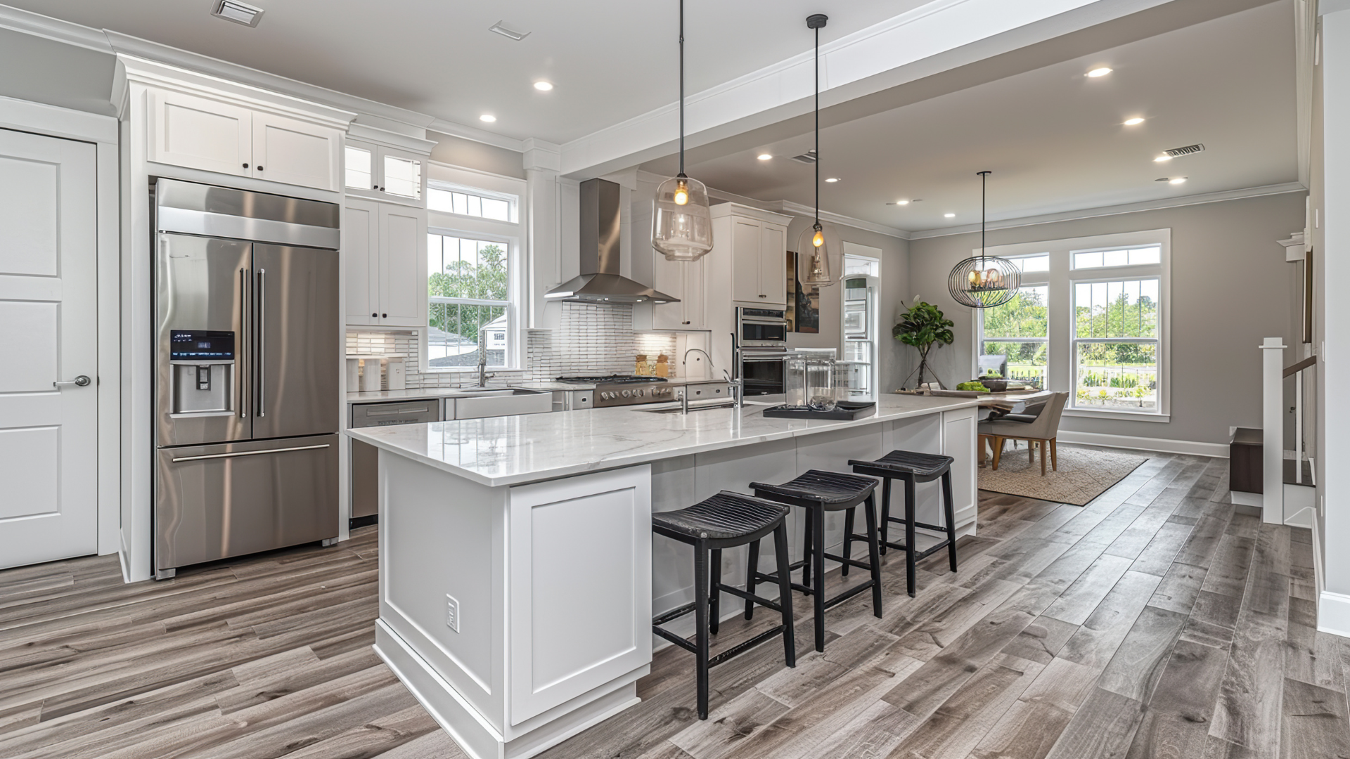 Bright modern kitchen with white cabinets, island, barstools, stainless appliances, and large windows