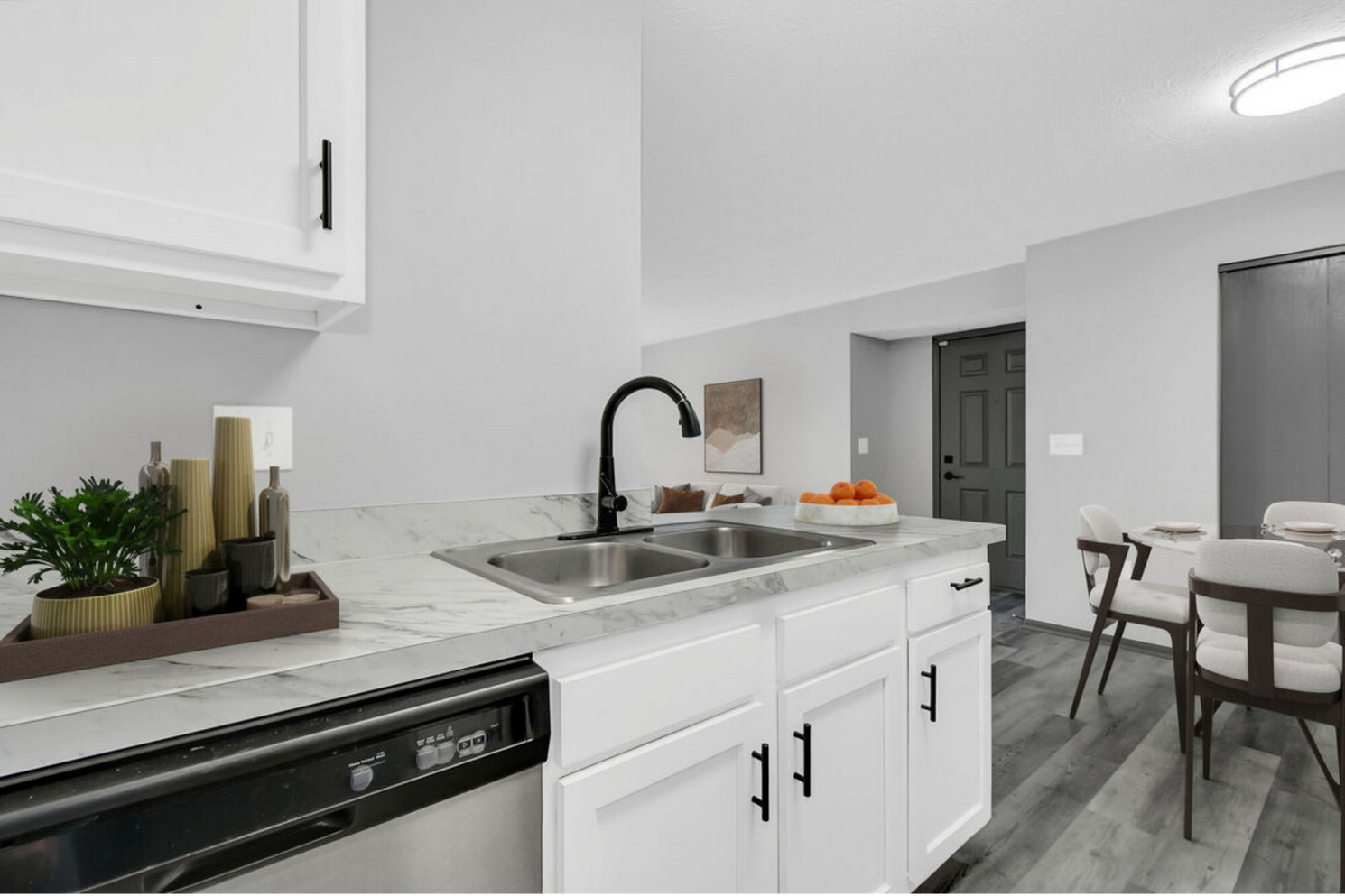 Bright modern kitchen with white cabinets, black faucet, and dining table in the background