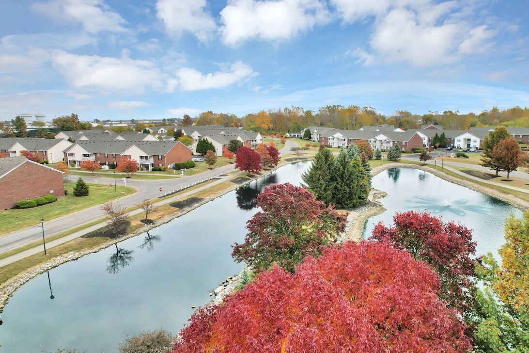 Suburban neighborhood with winding canals, autumn trees, and brick houses under a cloudy sky