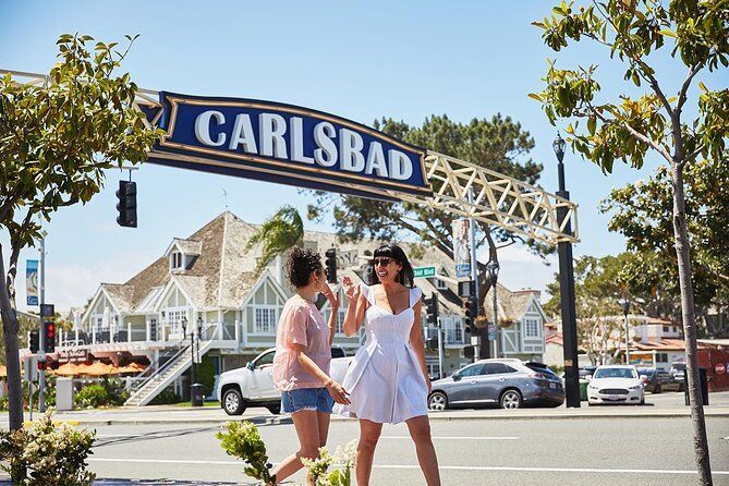 Two women are walking down the street under a carlsbad street sign.