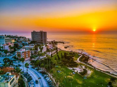 An aerial view of a city near the ocean at sunset.