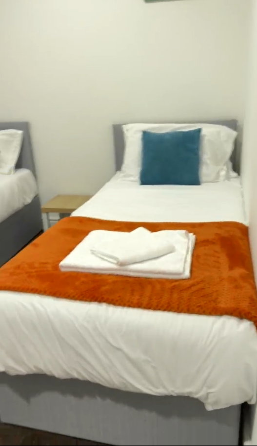 Freshly styled twin beds with folded towels, ready for the next guest after a SafiKleen short-let turnaround clean in Peterborough