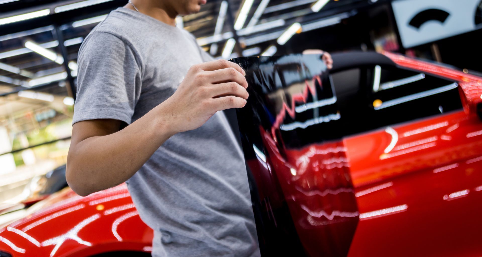 Applying tinting foil on a car window in a auto service.