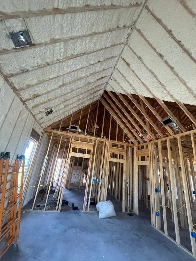 Interior of a house under construction with exposed framing, vaulted ceiling, and a ladder in the hallway