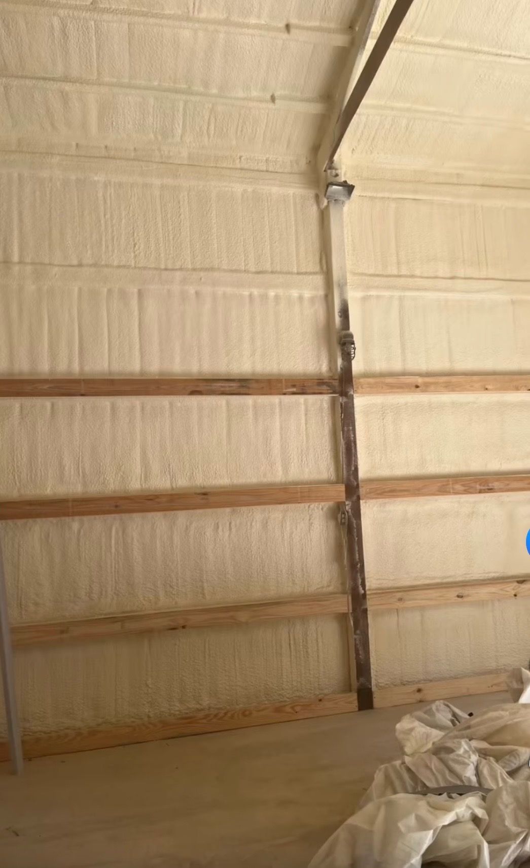 Interior of an unfinished room with insulated walls, exposed metal framing, and construction materials on the floor