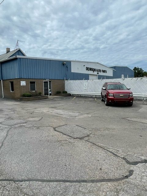 A red SUV is parked in front of a blue and tan warehouse building labeled 